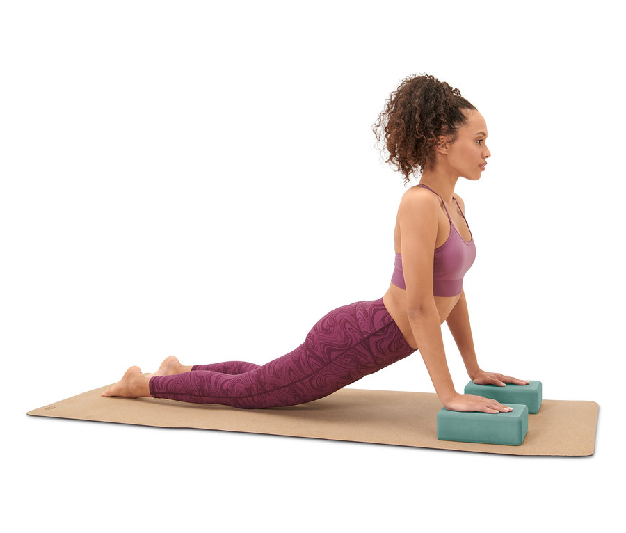 Kobieta wykonuje pozycję kobry na macie do jogi z zestawem do jogi.