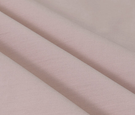 Zbliżenie na fałdy bladoróżowej pościeli perkalowej w rozmiarze standardowym i niestandardowym.