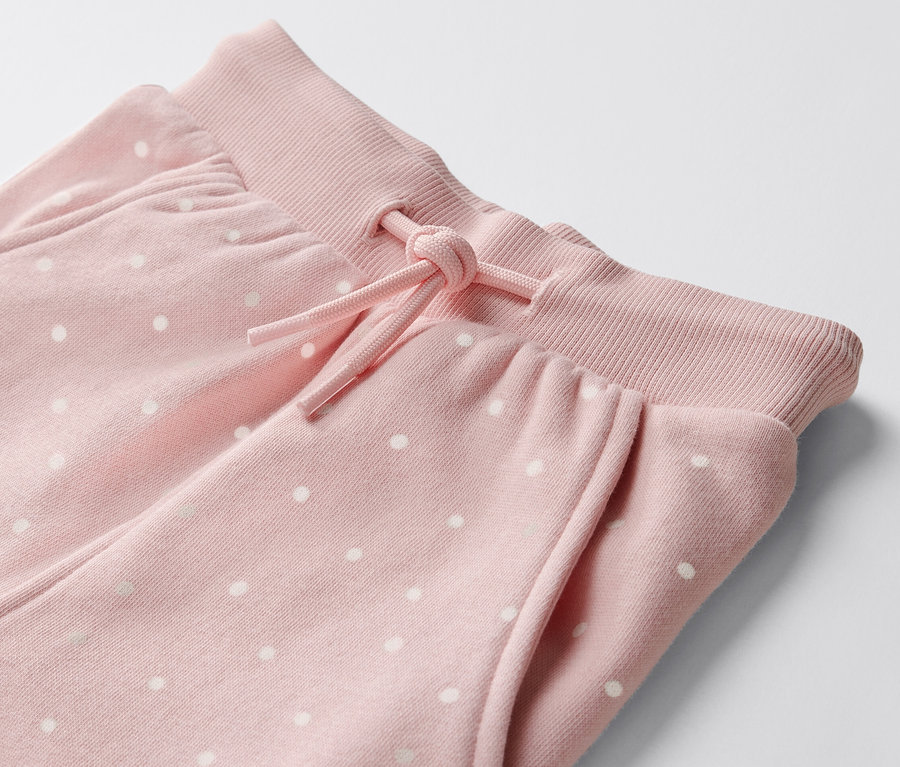 Zbliżenie na parę niemowlęcych spodni dresowych w kropki.