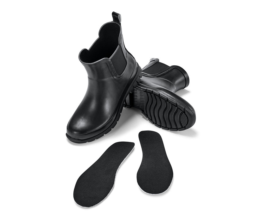 Dwie pary czarnych dziecięcych sztybletów przeciwdeszczowych i dwie czarne wkładki do butów na białym tle.
