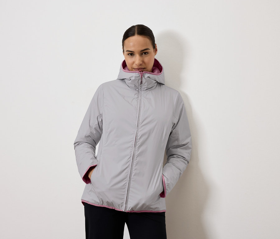 Kobieta ma na sobie szarą kurtkę z kapturem z fioletową podszewką.