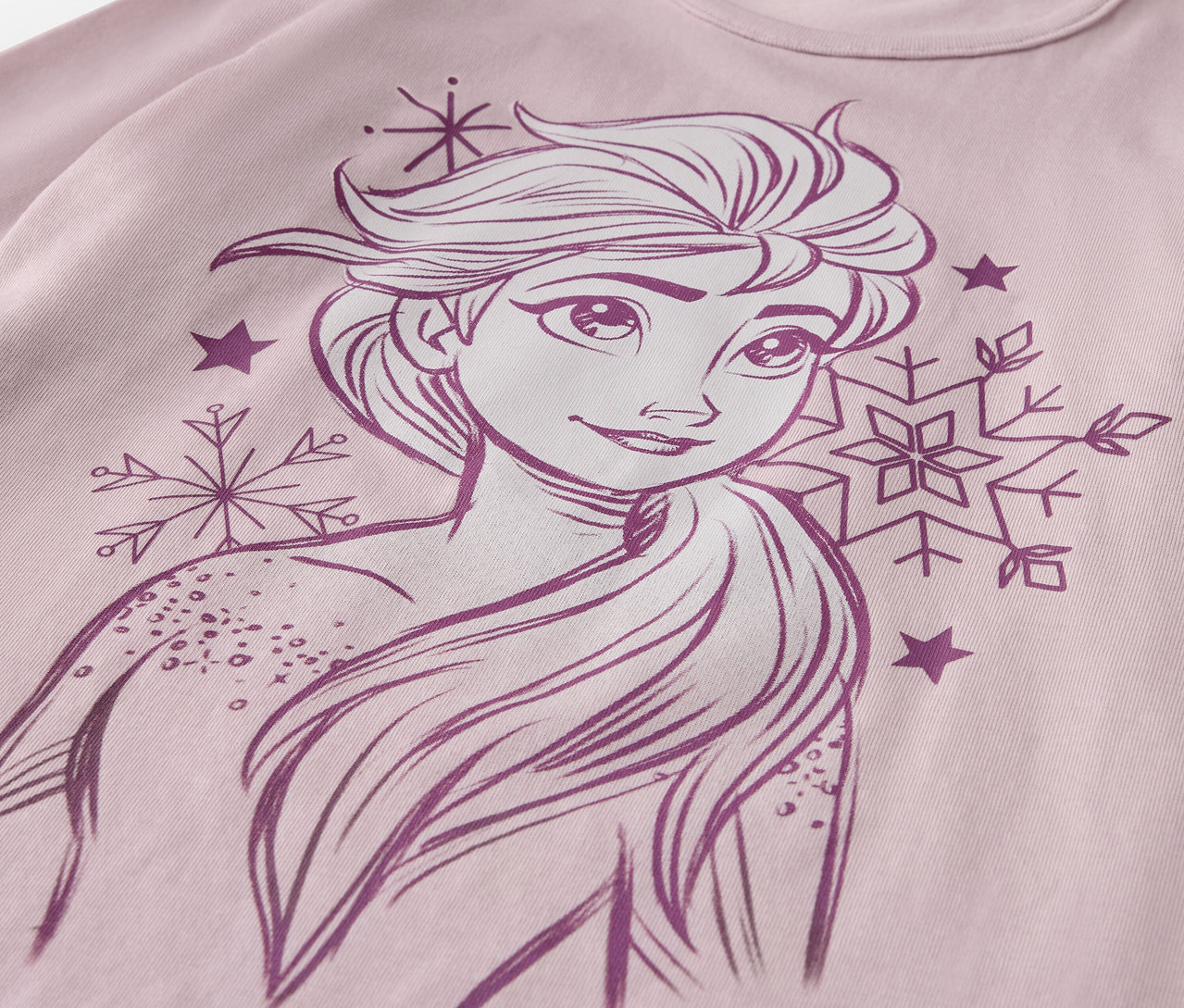 Zbliżenie na piżamę „Kraina lodu” z rysunkiem Elsy, płatkami śniegu i gwiazdami na różowej koszulce.