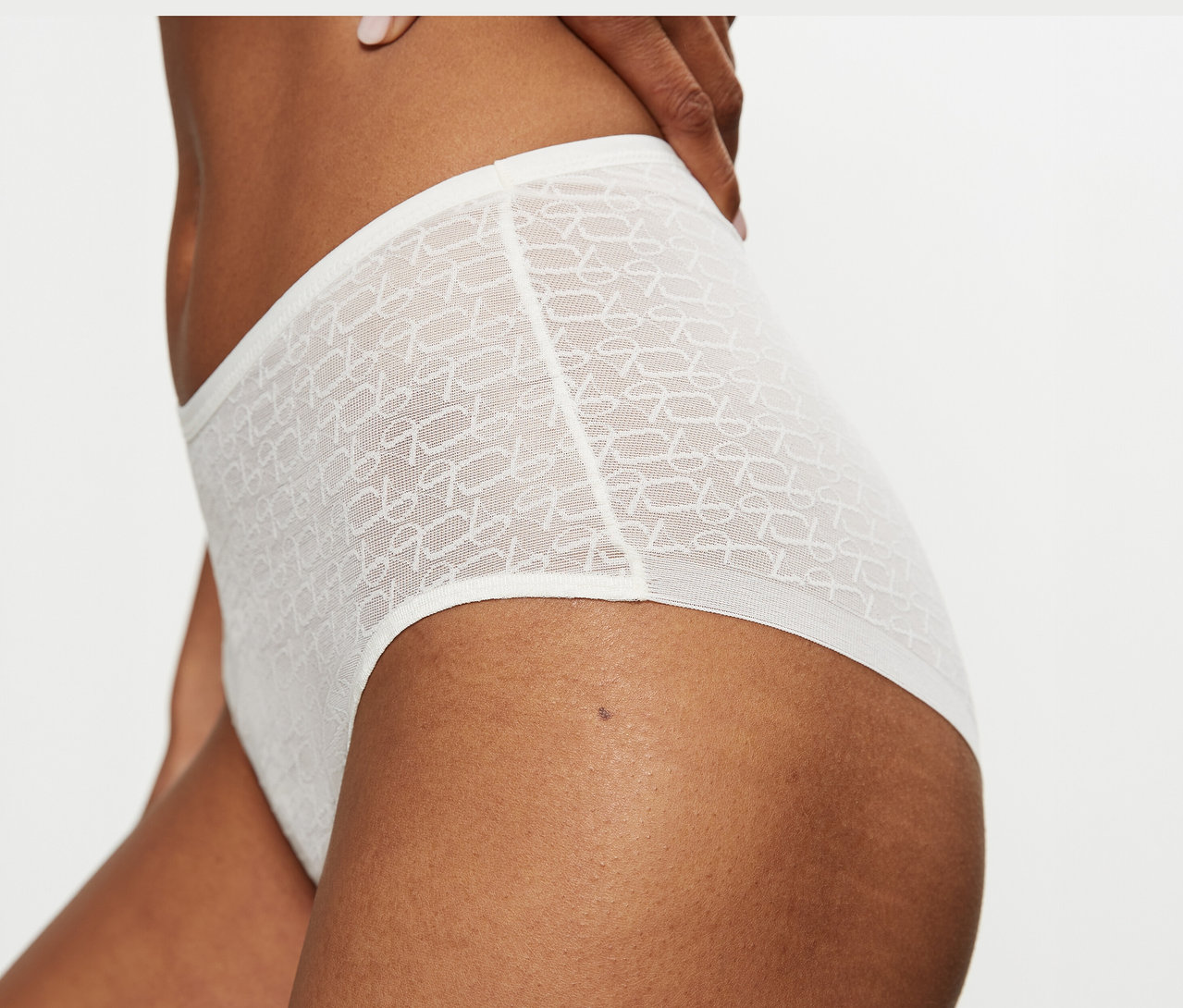 Zbliżenie na osobę w wysokich, przezroczystych figach Triumph Signature Sheer Maxi EX w kolorze Ecru White z wzorem.