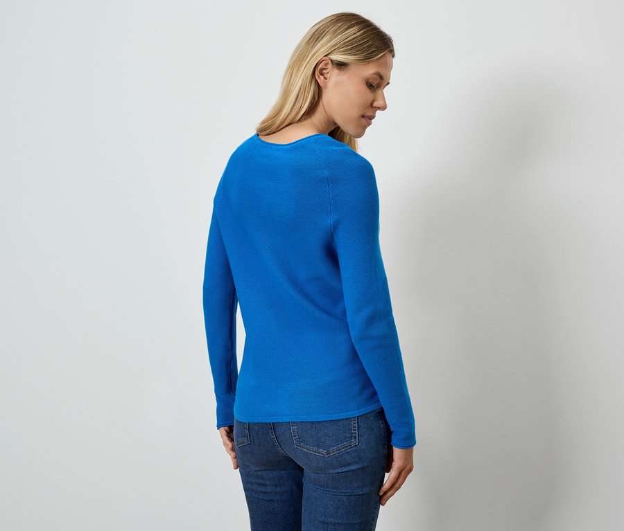 Kobieta widziana z tyłu ma na sobie niebieski top i dżinsy.