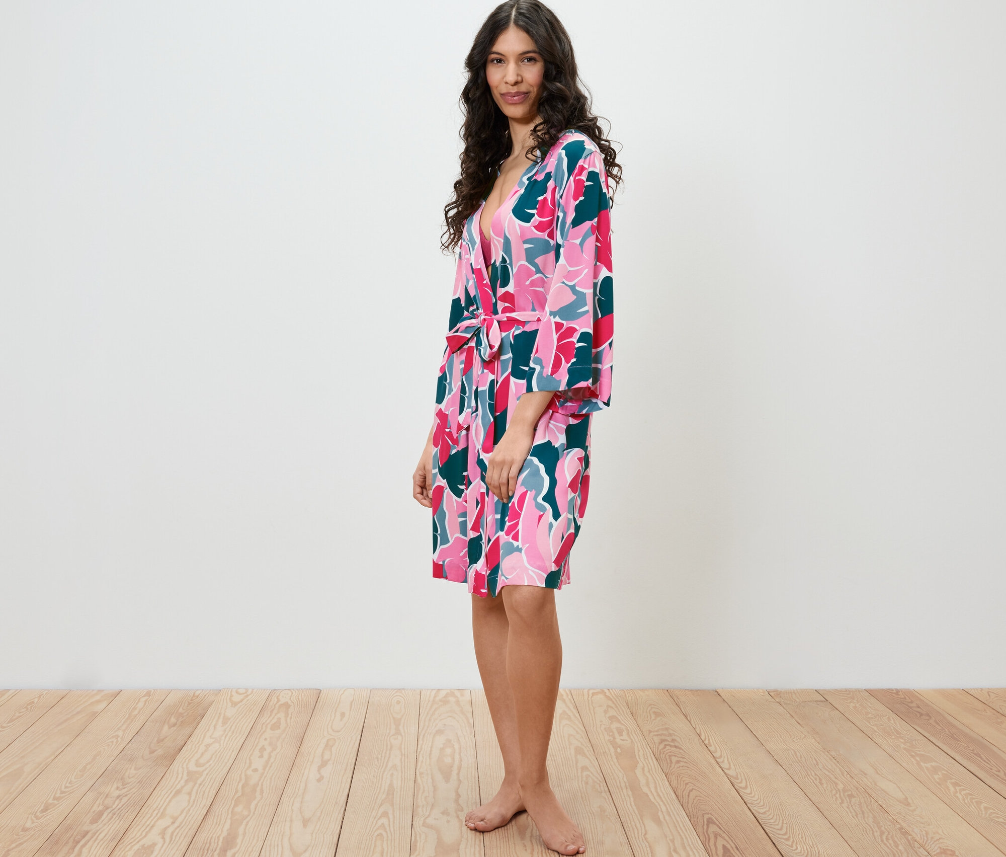 Kobieta stoi bokiem, ubrana w szlafrok w kwiatowy wzór.