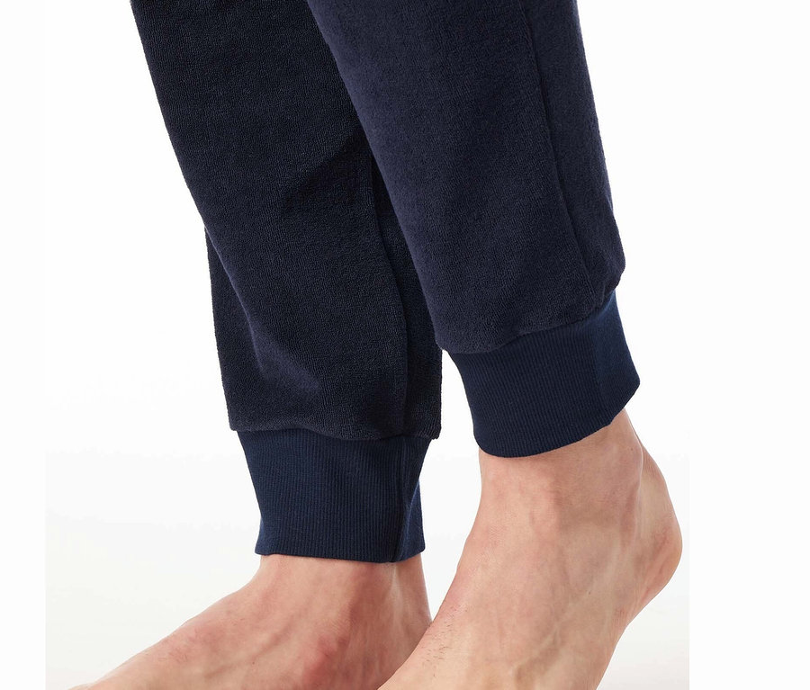 Zbliżenie stóp i dołu granatowych spodni dresowych.