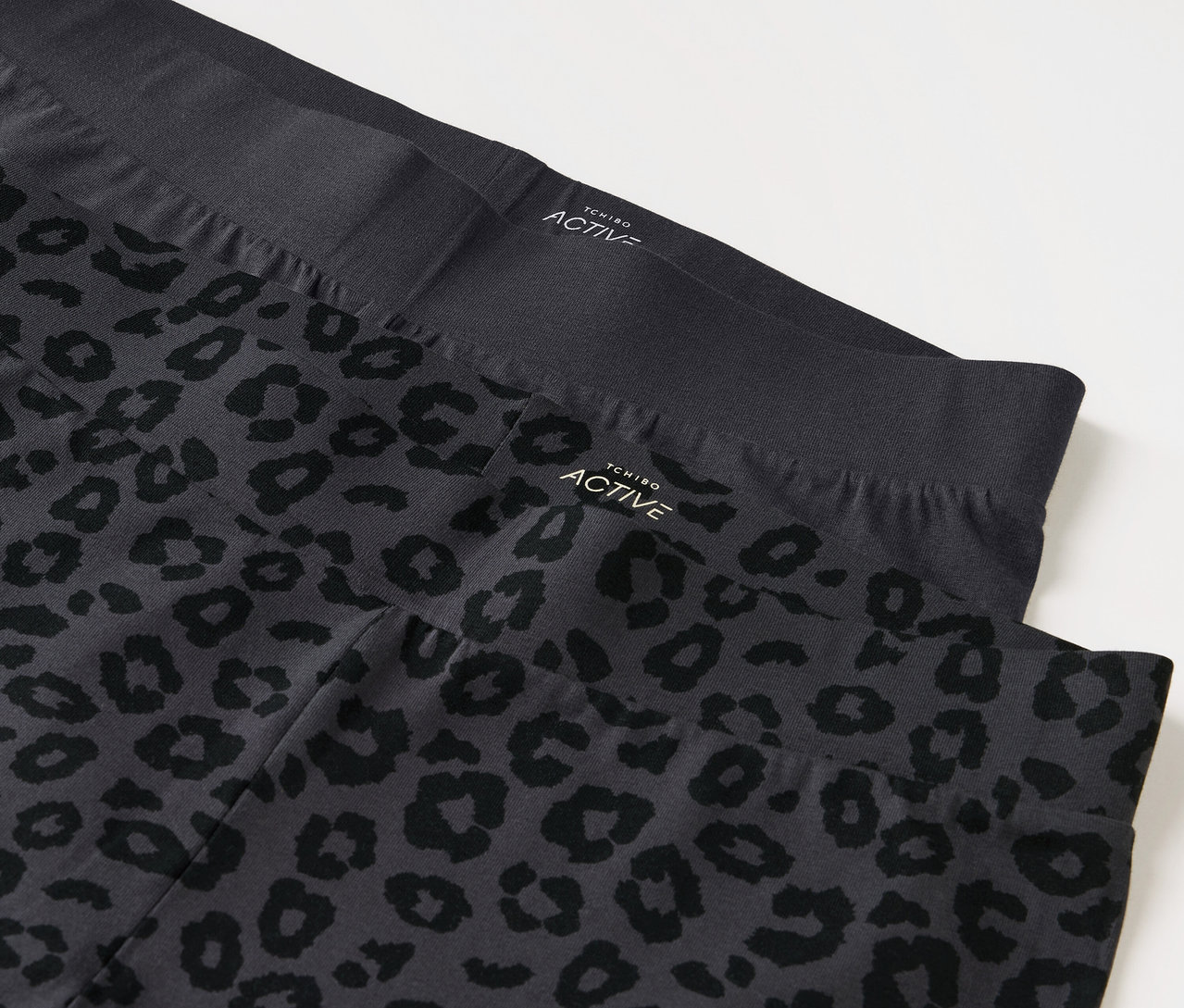 Dwa legginsy, jedne czarne i jedne szare we wzór zwierzęcy.