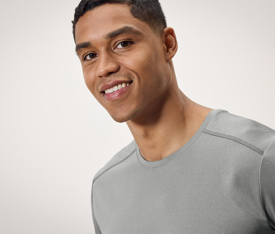Portret uśmiechniętego mężczyzny w szarej koszulce.