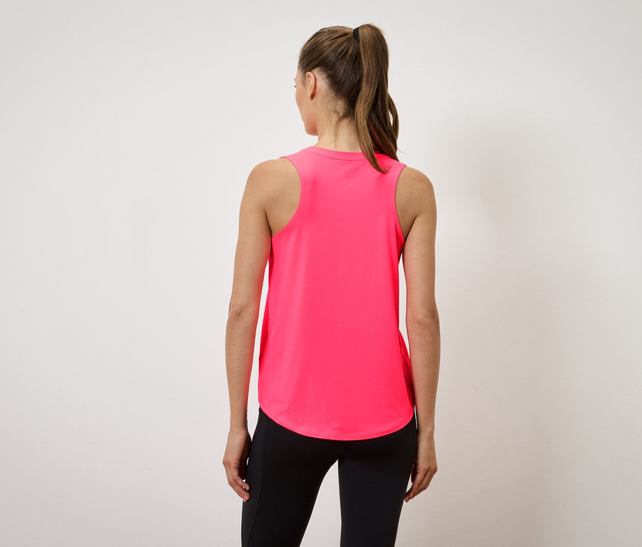 Kobieta w różowym topie i czarnych legginsach stoi tyłem do kamery.