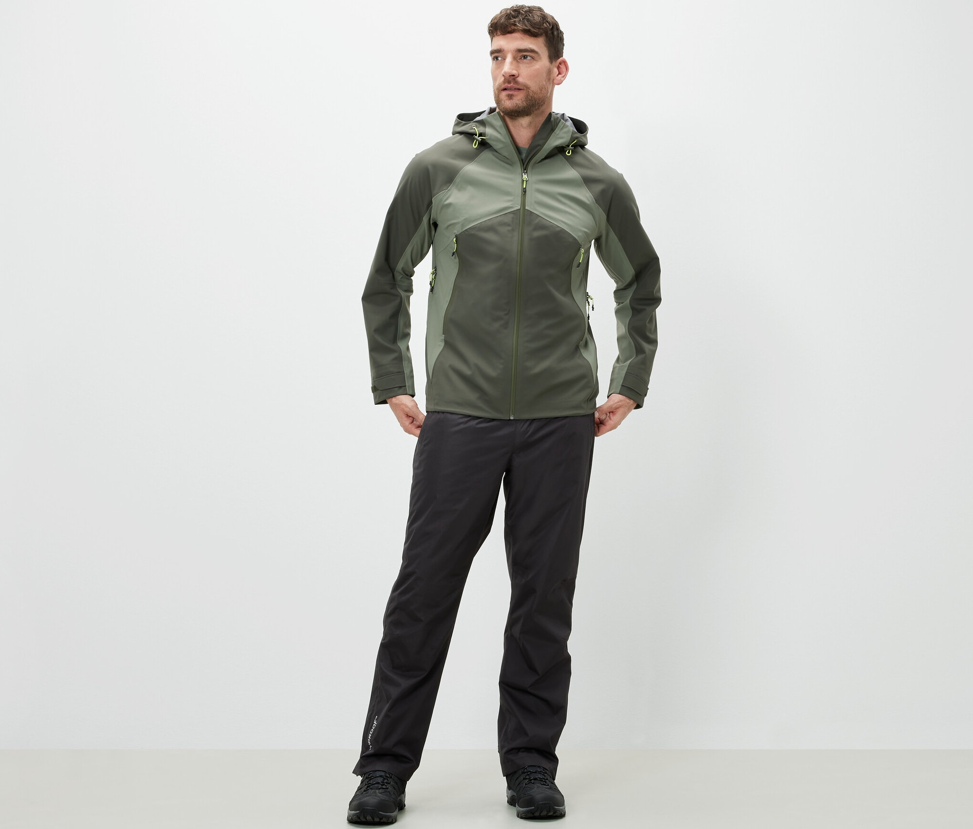 Mężczyzna stoi i ma na sobie spodnie przeciwdeszczowe i kurtkę.