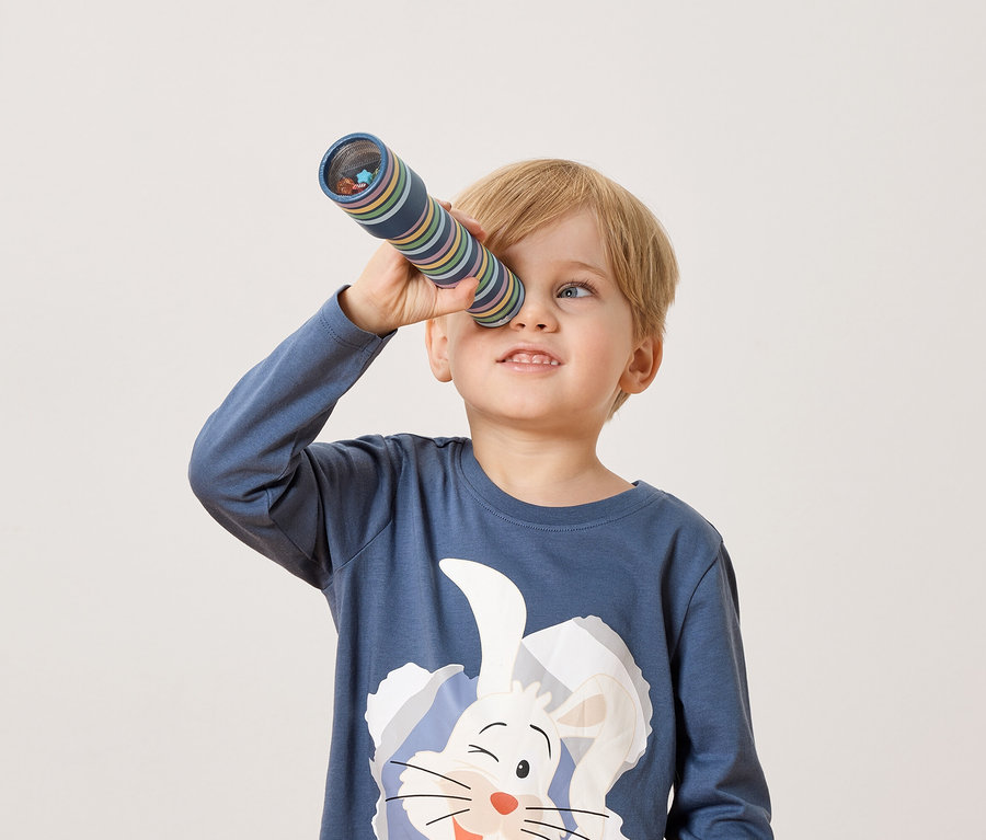 Blondwłosy chłopiec patrzy przez kalejdoskop.