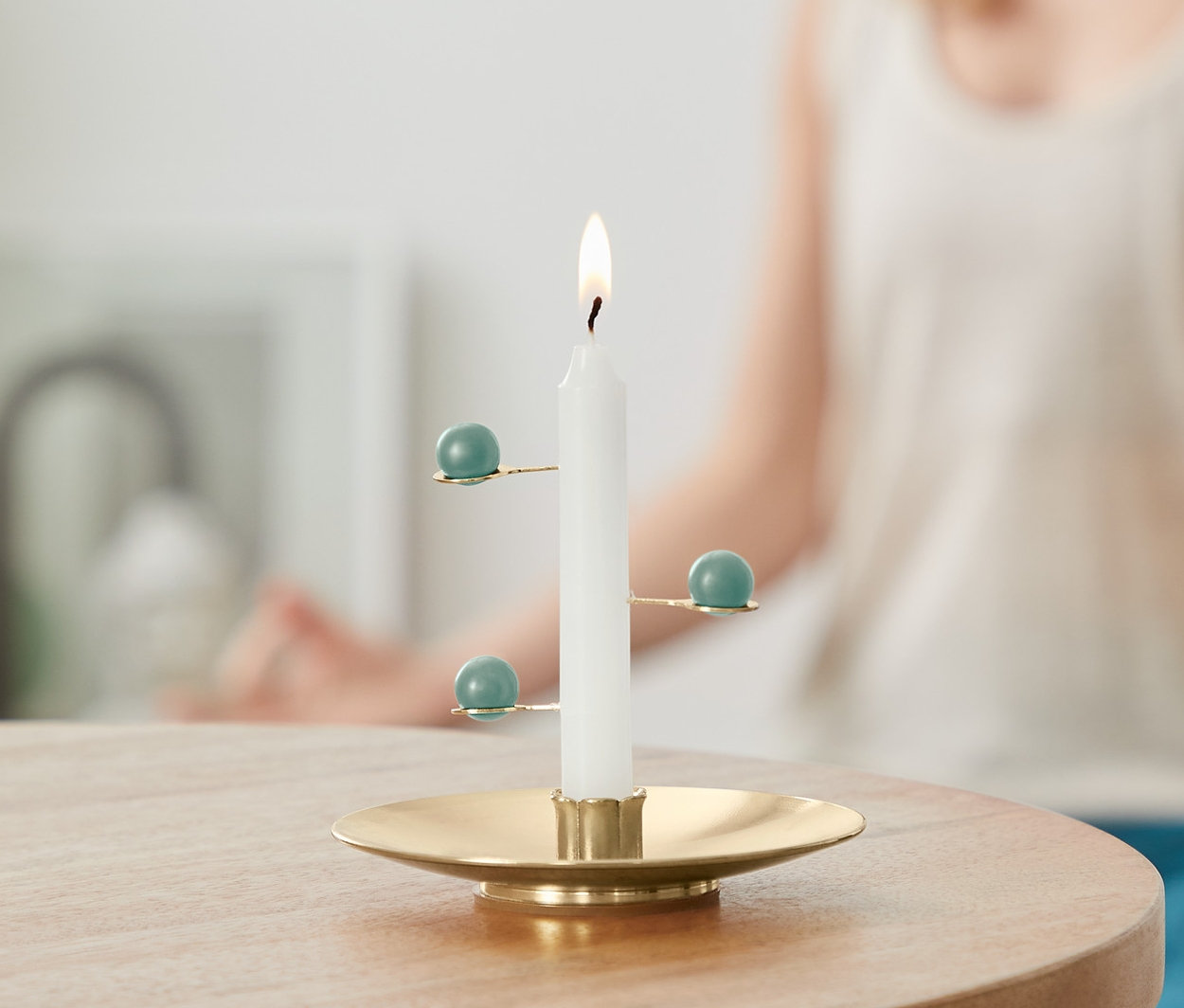 Płonąca Świeca do medytacji na stole, w tle kobieta w pozycji medytacyjnej.