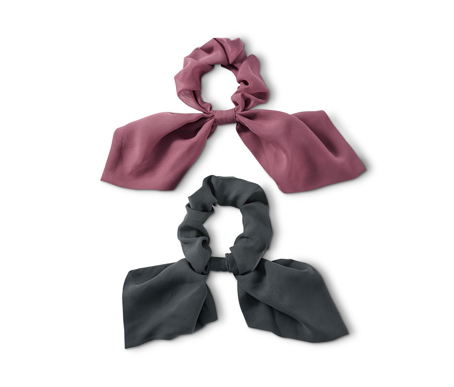 Dwie gumki do włosów z kokardką leżą na białym tle.