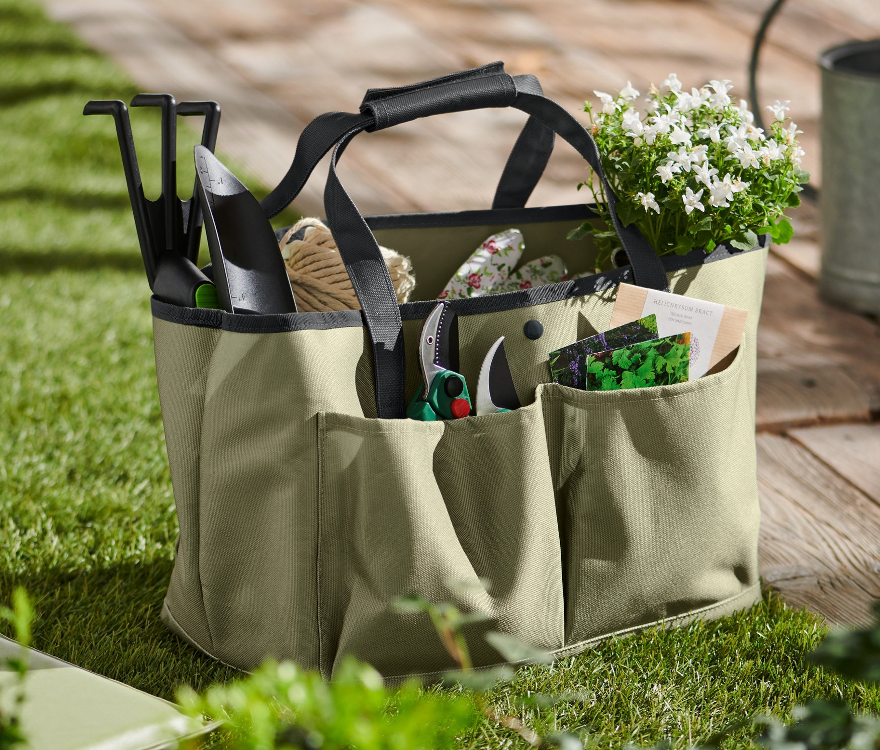 Narzędzia ogrodowe w torbie ogrodniczej na trawie.