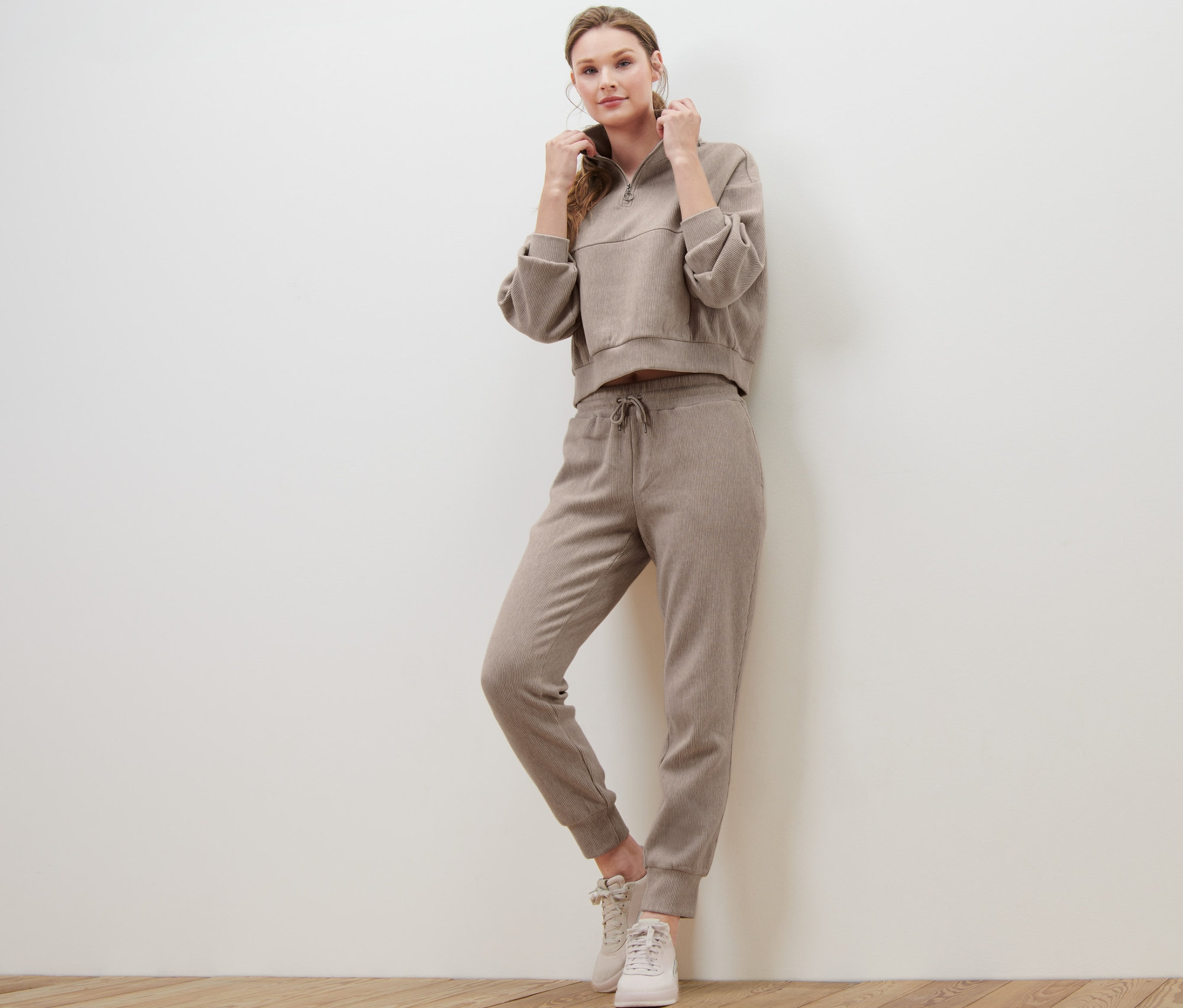 Kobieta pozuje w spodniach dresowych i bluzie.