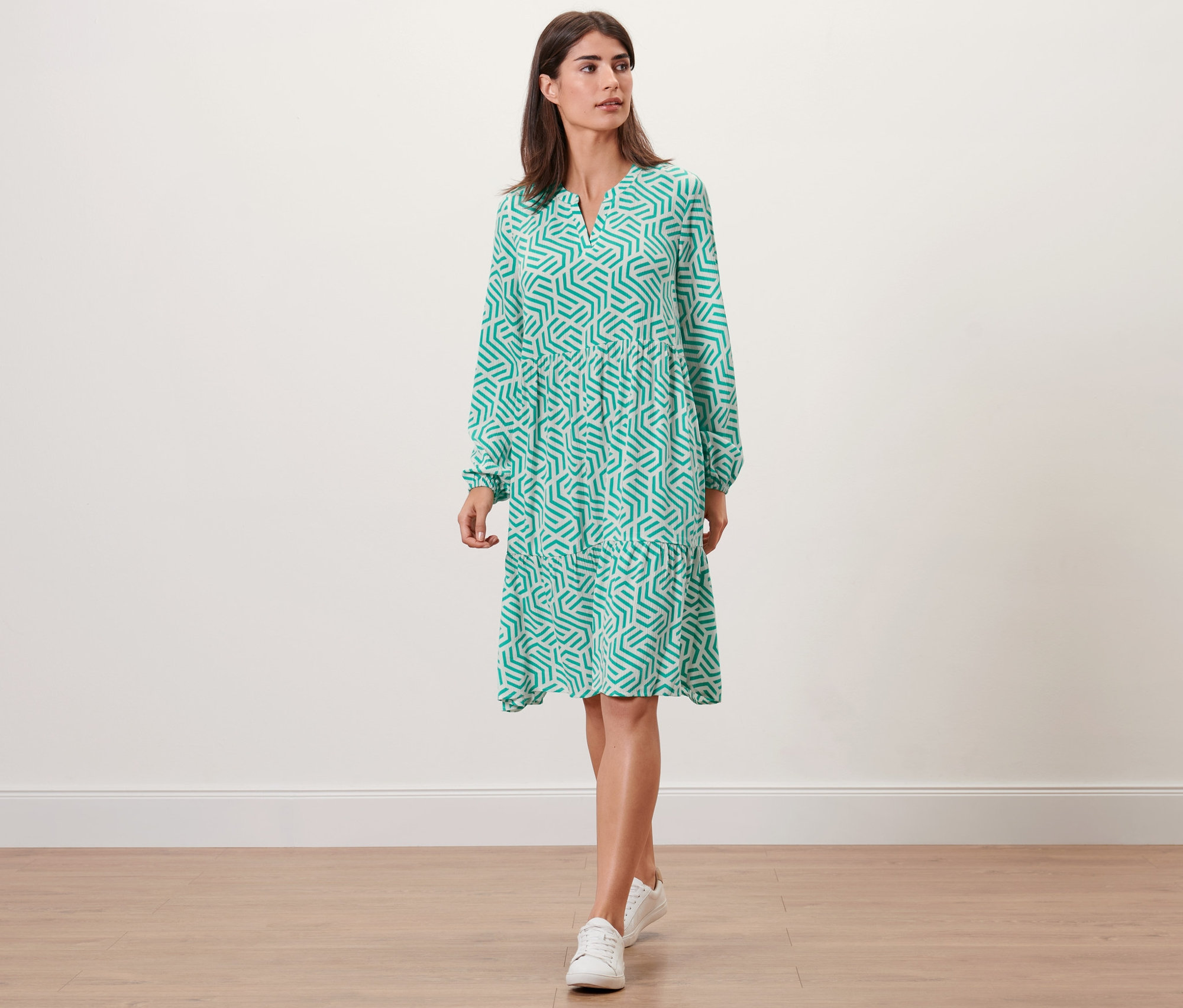 Kobieta idzie w sukience z tkaniny z nadrukiem, aqua.
