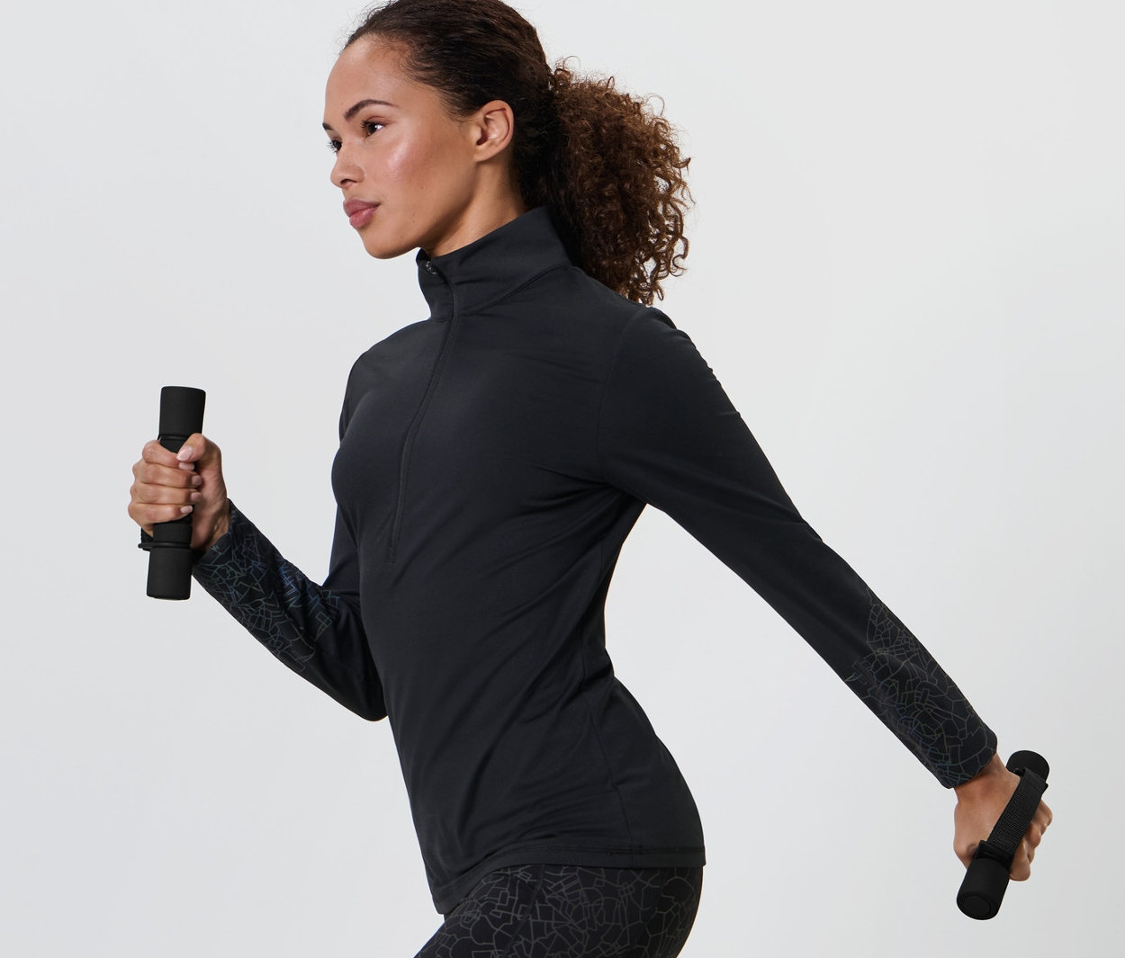 Kobieta w czarnym stroju sportowym trzyma w każdej ręce ciężarki do biegania i ćwiczeń, 2 sztuki.