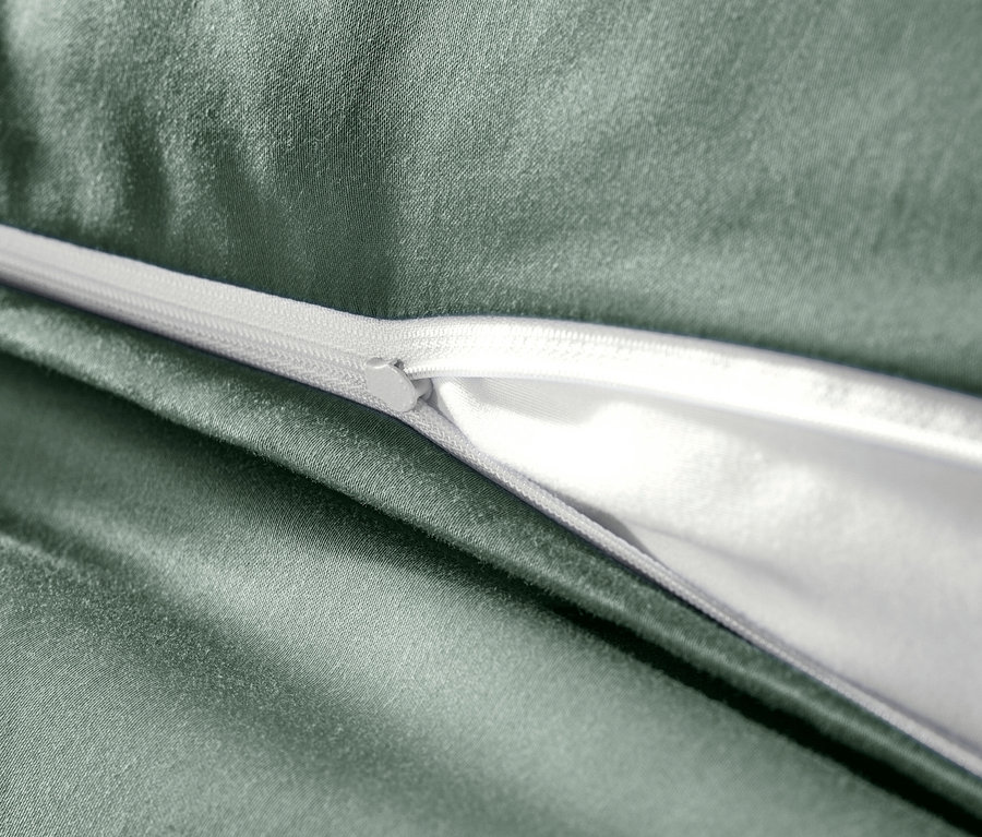 Zbliżenie na zieloną pościel z satyny bawełnianej z zamkiem błyskawicznym.