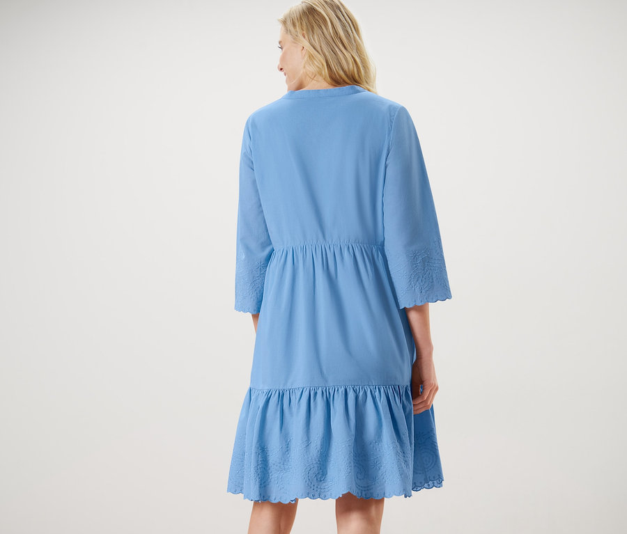 Kobieta ma na sobie sukienkę z tkaniny z haftem.