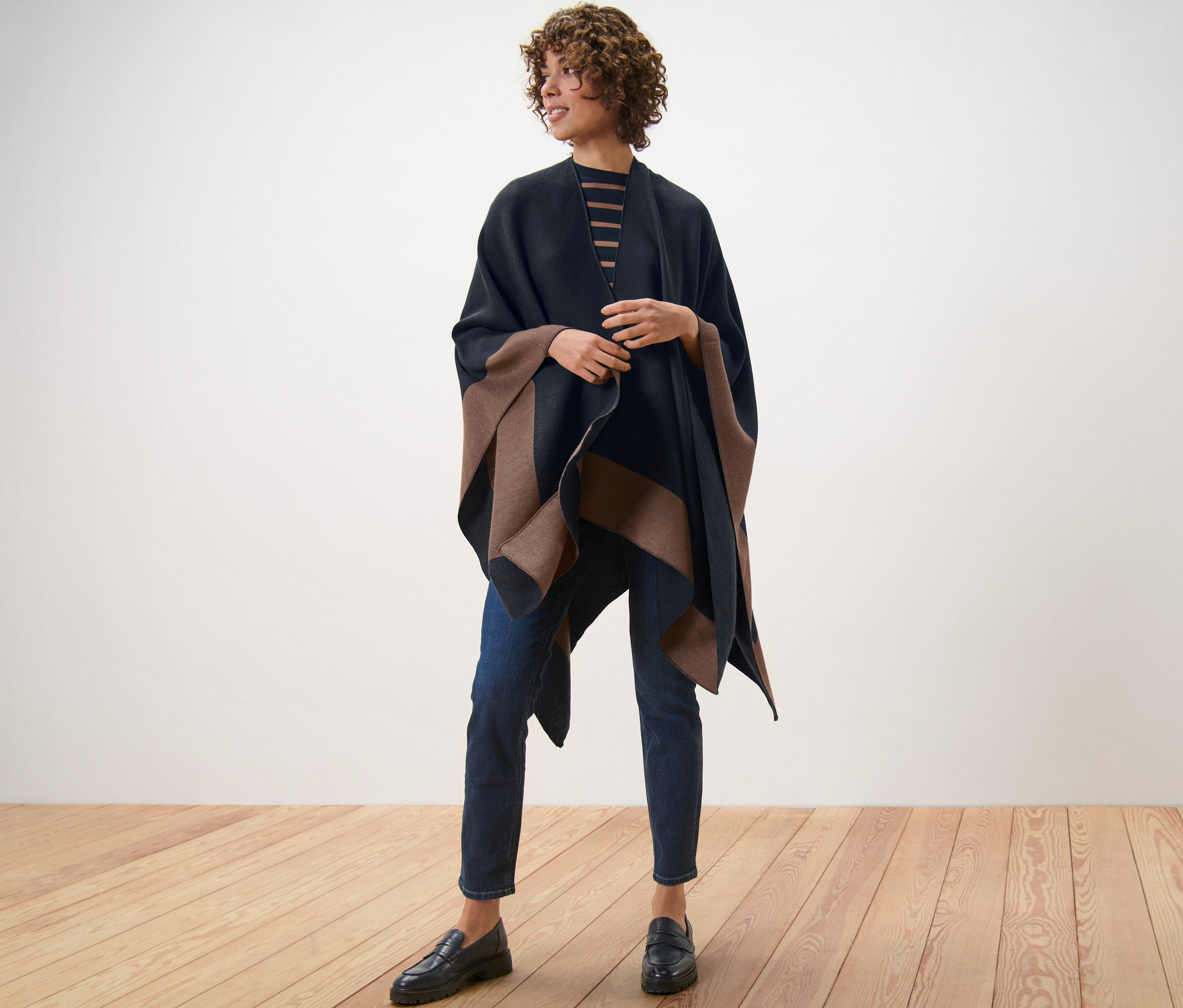 Kobieta stojąca na drewnianej podłodze ma na sobie dwustronne poncho.