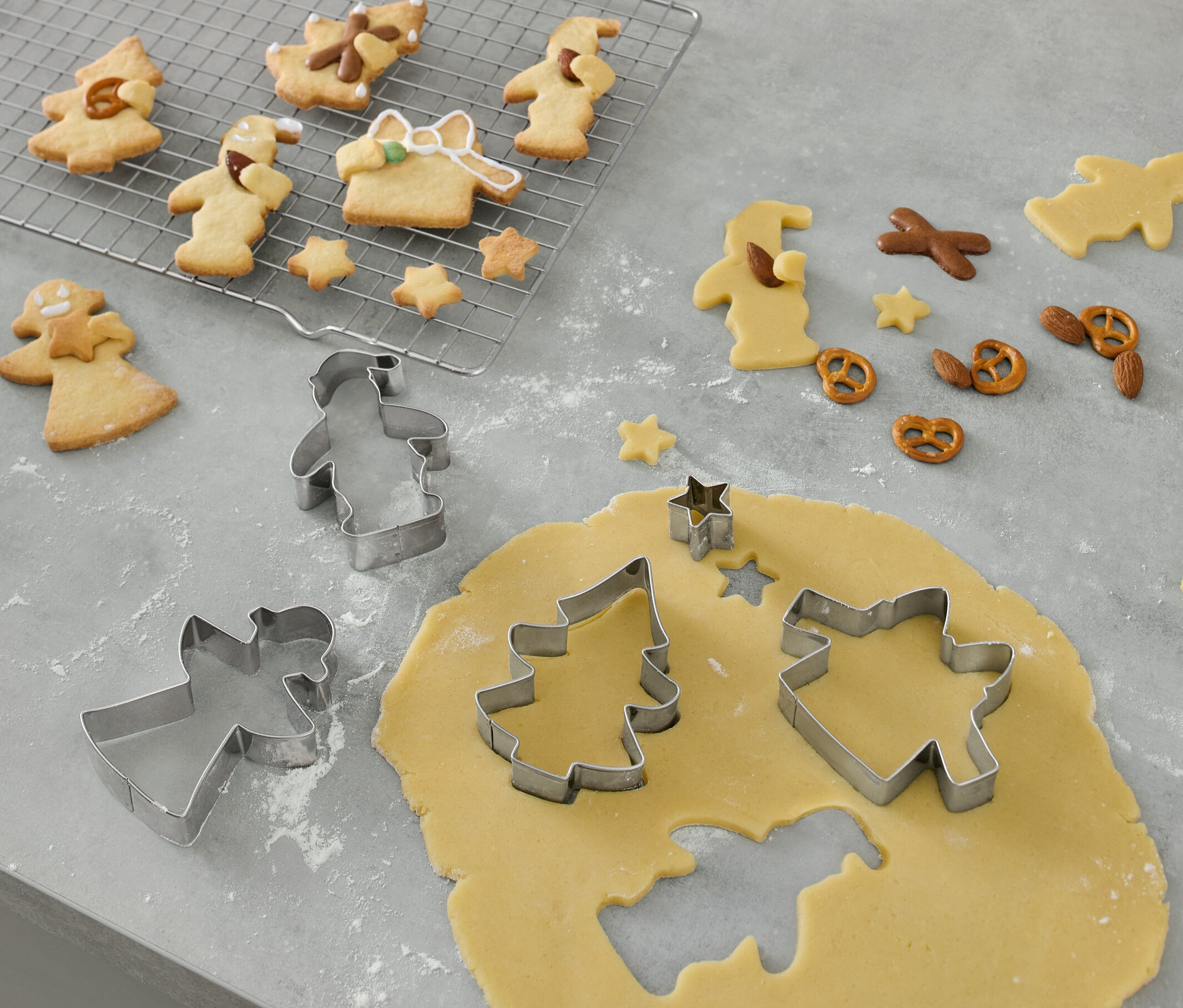 Foremki do wykrawania ciastek, 5 sztuk, leżą na wałku i wycinają kształty z ciasta na ciasteczka.