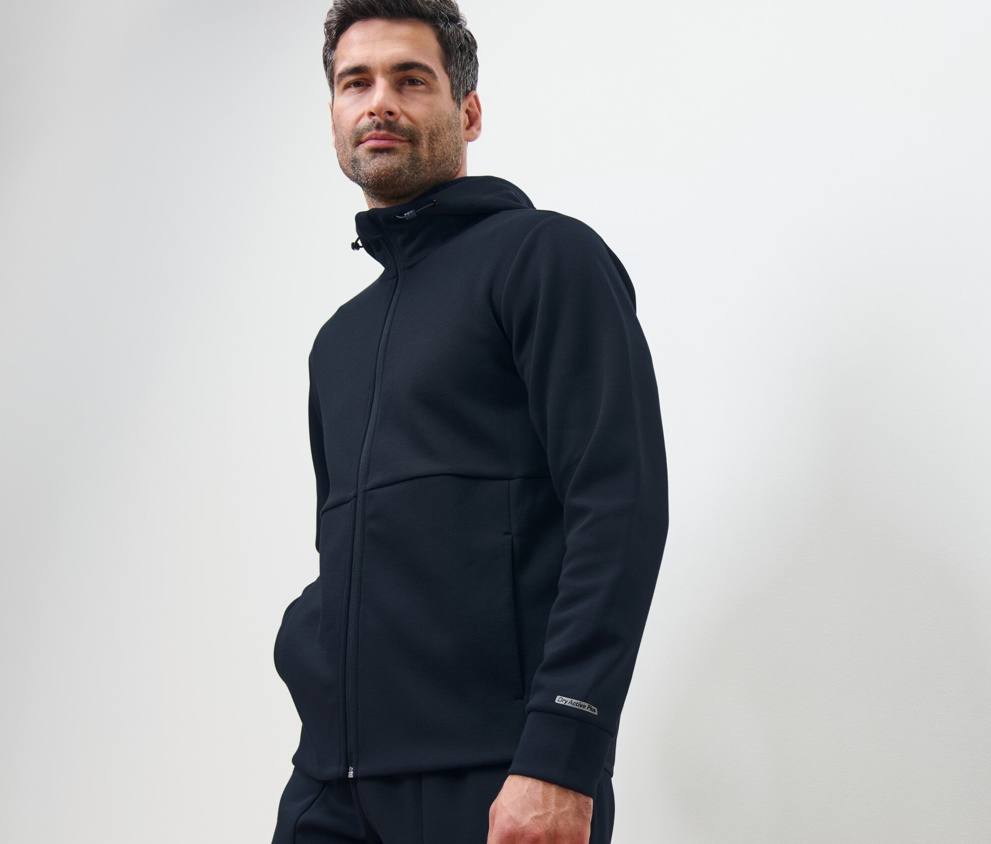 Mężczyzna pozuje w granatowej funkcyjnej bluzie dresowej.