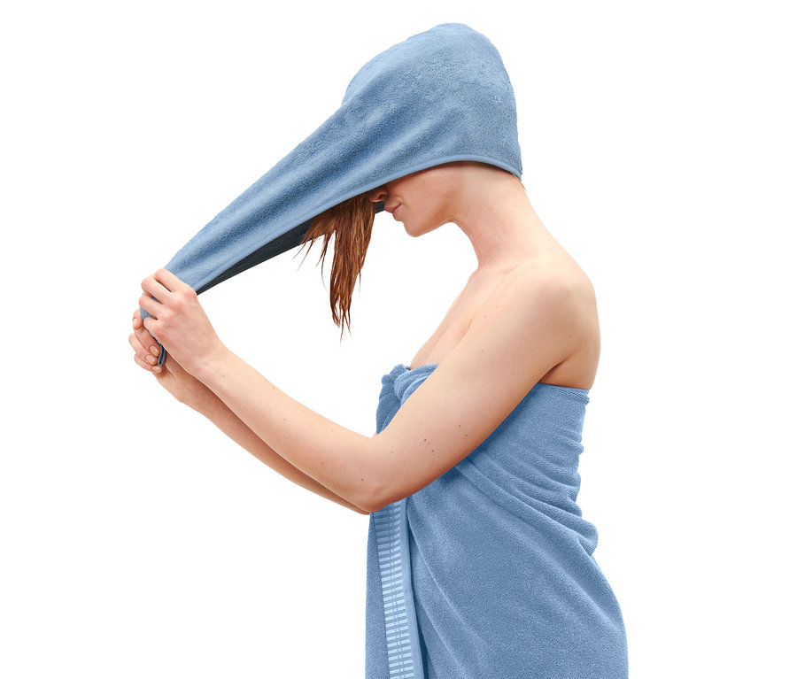 Kobieta owija głowę niebieskim ręcznikiem-turbanem.