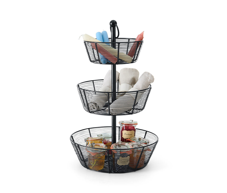 Czarna etażerka z trzema koszykami z słoikami i świecami.