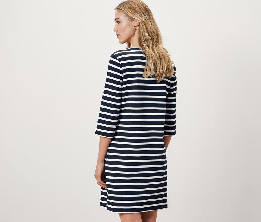 Kobieta stoi tyłem w sukience dresowej w paski.