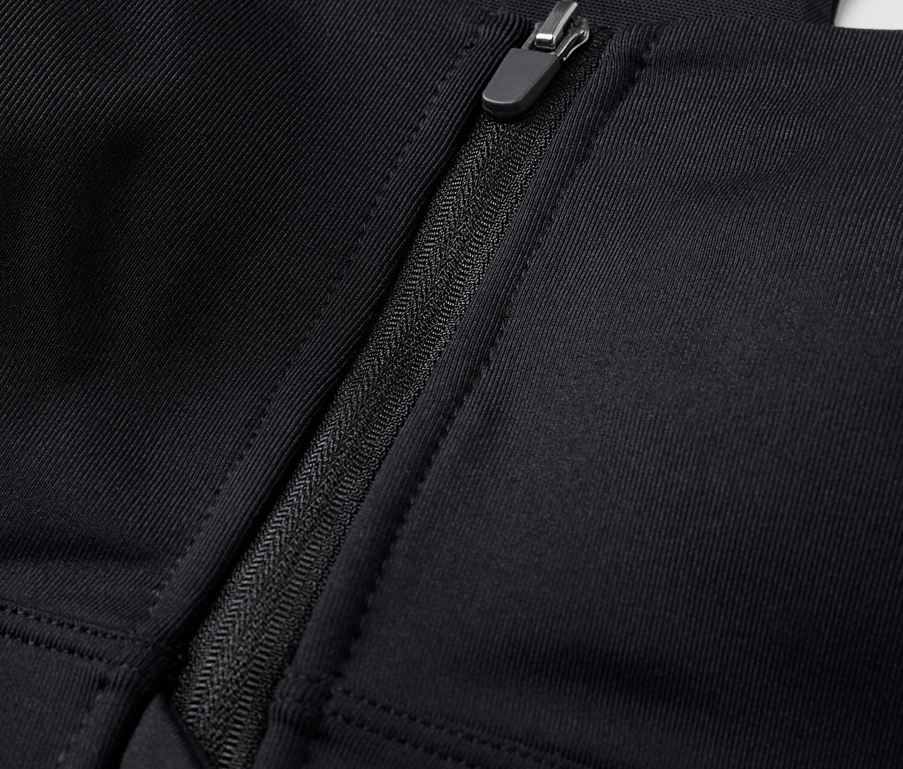 Zbliżenie na czarny biustonosz sportowy zapinany z przodu na zamek błyskawiczny.