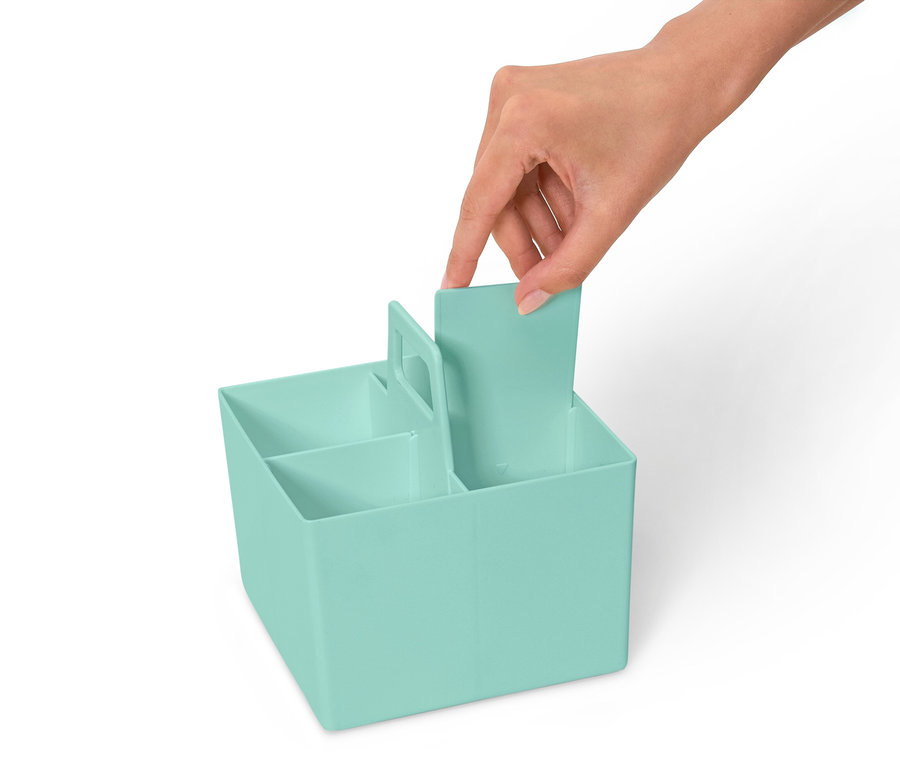 Ręka wkłada przegródkę do jasnoniebieskiego organizera z kilkoma przegródkami.