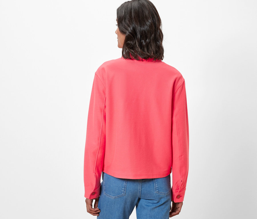 Widok z tyłu kobiety w kurtce z dżerseju i dżinsach.