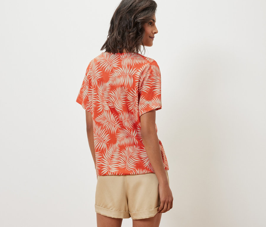 Kobieta ma na sobie wzorzystą bluzkę i szorty.