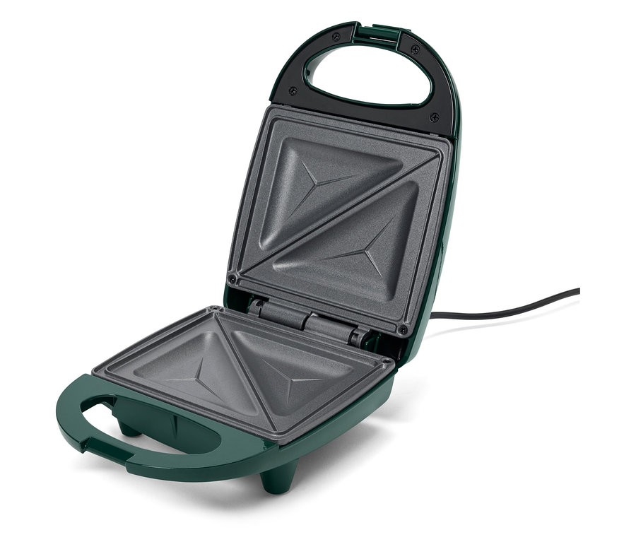 Otwarty, zielony opiekacz do kanapek z trójkątnymi wgłębieniami.
