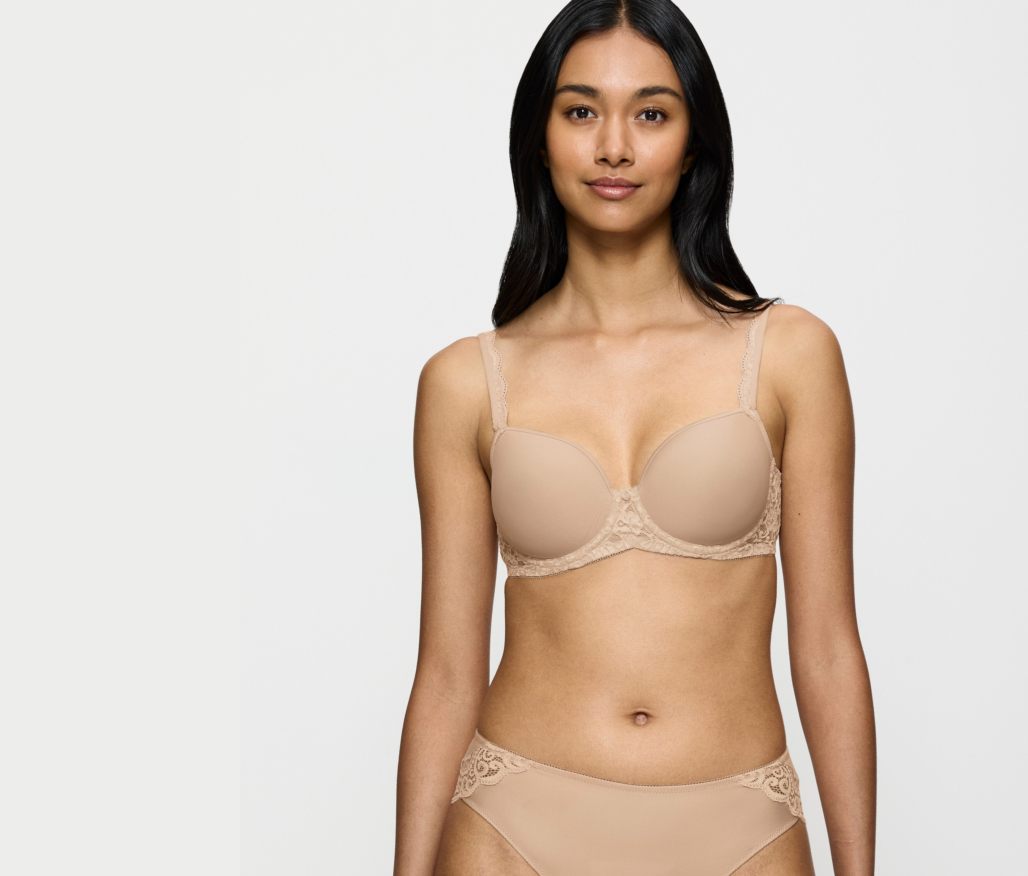 Kobieta ma na sobie beżowy biustonosz i majtki z koronkowymi detalami.