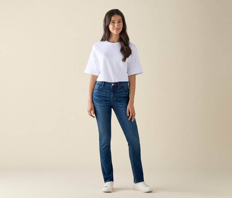 Kobieta stoi i ma na sobie Slim-Jeans – Fit »Emma«, mid blue denim i biały T-shirt.