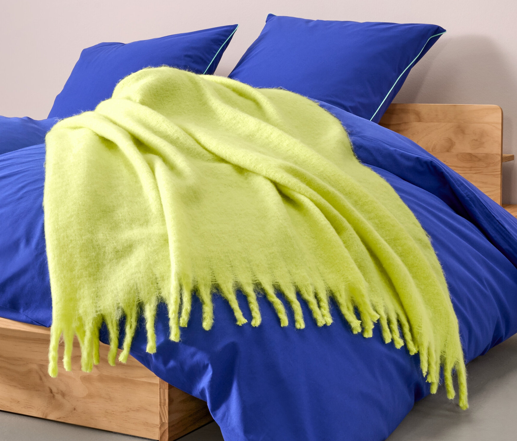 Limonkowa narzuta, ok. 130 x 150 cm, leży na niebieskim łóżku.