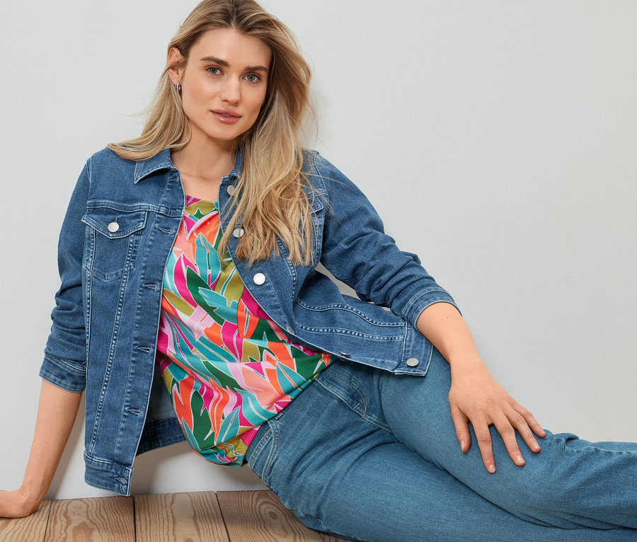 Kobieta siedzi na podłodze w kurtce dżinsowej.