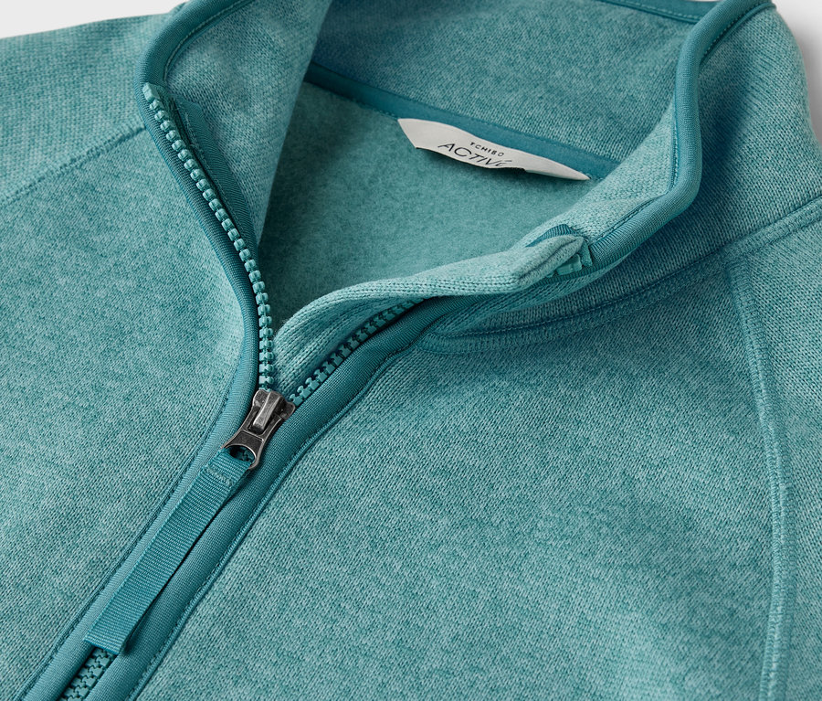 Zbliżenie na niebiesko-zieloną bluzę polarową z zamkiem błyskawicznym.
