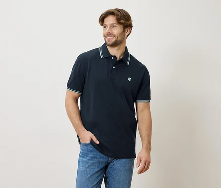 Mężczyzna w granatowej koszulce polo i jeansach