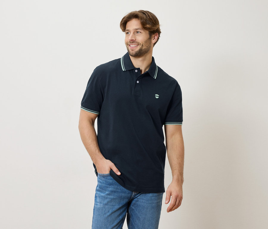 Mężczyzna w granatowej koszulce polo i jeansach