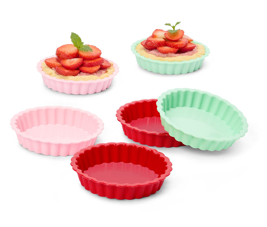 Kilka kolorowych foremek do tart, niektóre wypełnione tartaletkami z truskawkami.