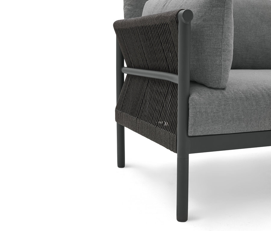 Kadr z bliska szarego krzesła z ciemnym sznurkowym obiciem z boku.