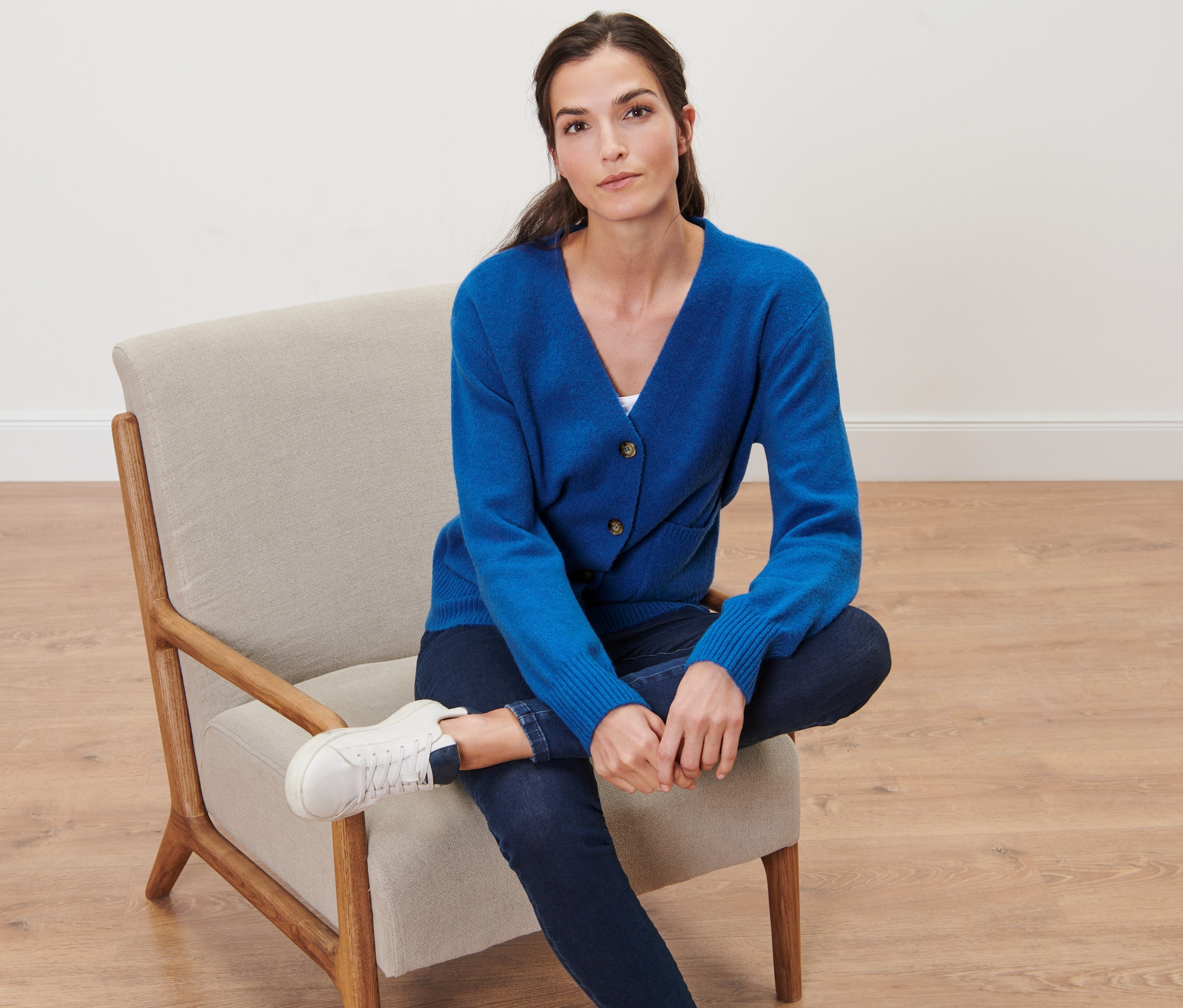 Kobieta siedzi na krześle i ma na sobie rozpinany sweter z zawartością wełny, kobaltowy.