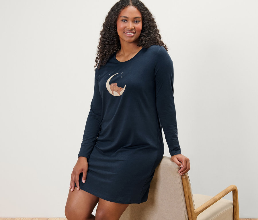 Kobieta oparta o krzesło ma na sobie niebieską koszulę nocną.