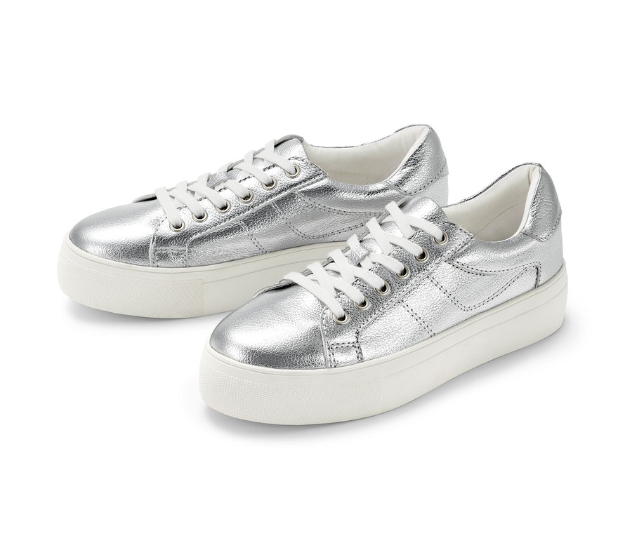 Dwa srebrne skórzane sneakersy na platformie leżą obok siebie na białym tle.