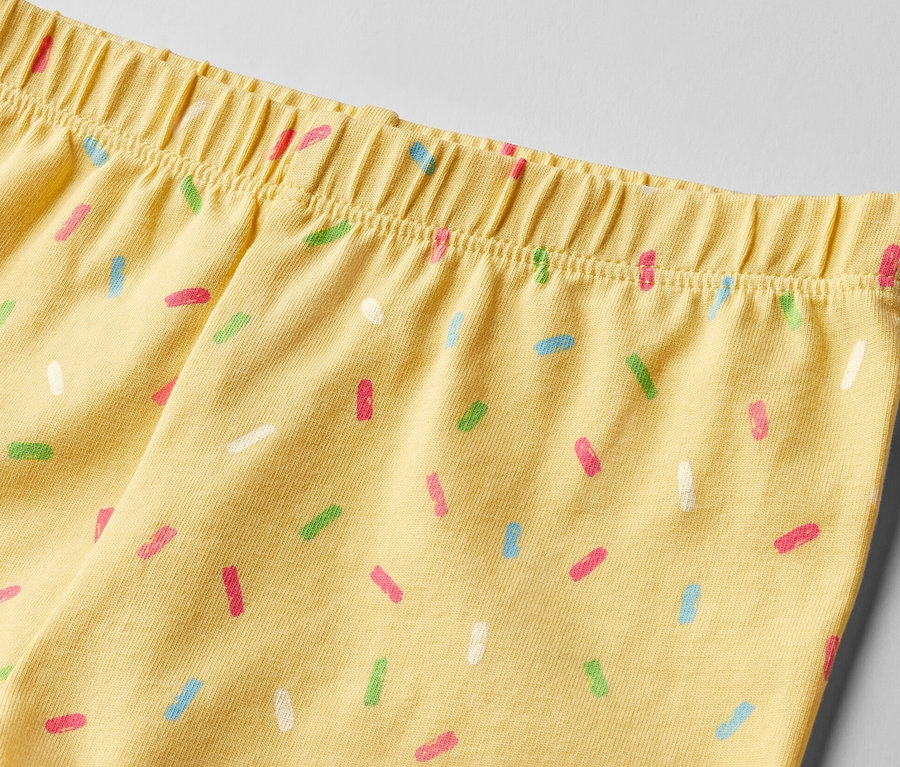 Zbliżenie na żółte krótkie legginsy dziecięce w kolorowe posypki, 2 pary.