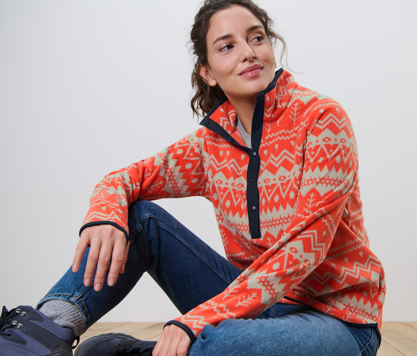 Kobieta siedzi na podłodze i ma na sobie bluzę z polaru.