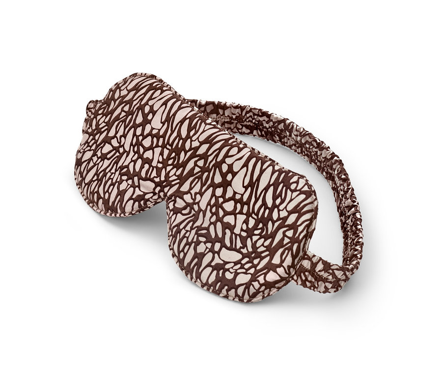 Brązowo-kremowa maska do spania leży na białym tle.