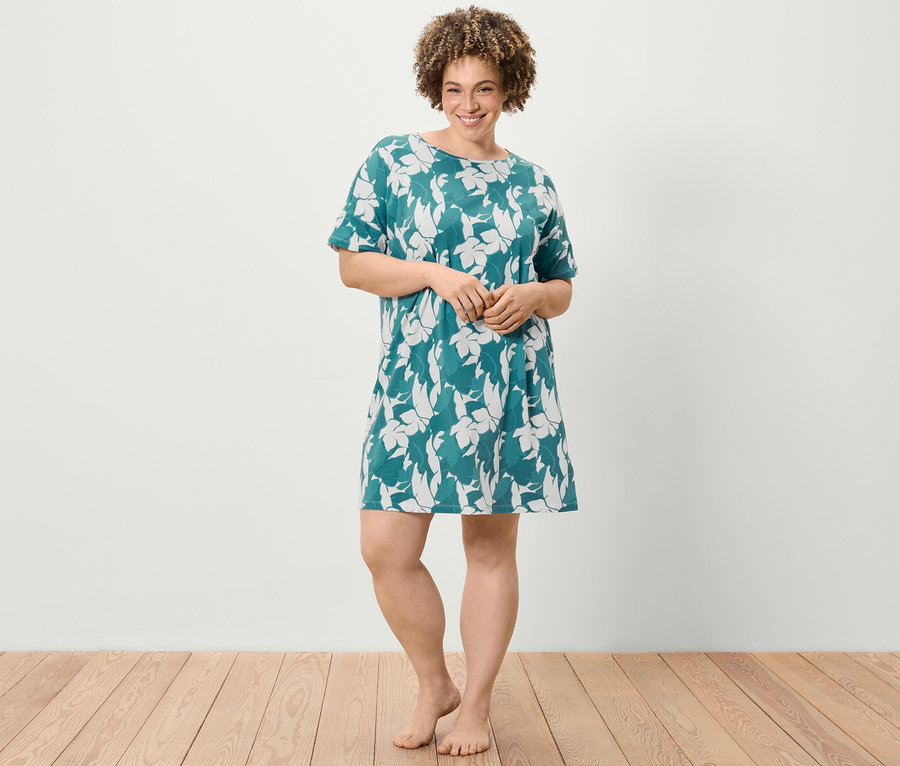 Kobieta stoi i ma na sobie koszulę nocną z krótkim rękawem i kwiatowym wzorem.